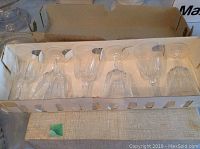 Five clear crystal stemmed wine glasses in box, stacked upside down in cardboard box