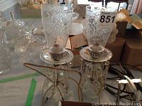 Two clear glass table lamps with tall etched glass shades and visible crystal droppings. Damaged cords are visible wrapped around the lamp bases.