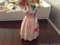 Front view of the Royal Doulton Miss Demure porcelain figurine with parasol and pink dress.