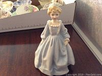 Front view of Royal Worcester porcelain figurine of a young girl in a blue dress with detailed facial features and soft pastel colors.