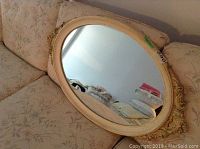 Full view of oval mirror on floral patterned sofa