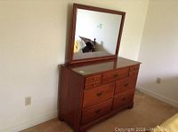 Full view of the wooden dresser with mirror attached on top.