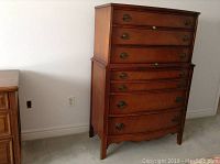 Front view of the tall wood highboy dresser showing seven drawers and brass hardware