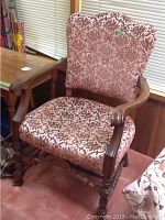 Front and side view of the wood and fabric armchair showing its patterned upholstery and carved wooden frame.