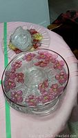 Large glass bowl with pink flower decorations on table, three small cut glass dishes on top of a platter with grape and leaf design