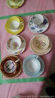 Top down view of the six teacups with matching saucers arranged on pink tablecloth
