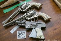 Two Hurley Cowboy Western toy revolvers and one Cody Colt LMCO toy cap gun displayed on a table, showing overall condition and design