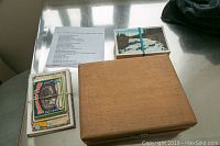 Photo showing a wooden box alongside two stacks of vintage postcards bound with rubber bands and a list describing the contents.