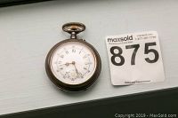 Front view of antique pocket watch showing white dial with Arabic numerals and ornate hands, alongside MaxSold lot number 875.