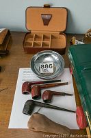 Five Dunhill pipes, ashtray bowl, suede pouch and partially visible green object on table