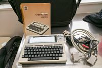 Overall view of Radio Shack TRS-80 Model 100 unit, manual and cables