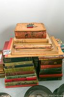 Two stacks of assorted hardcover books with a smaller pile on top, showing spine colors and overall quantity