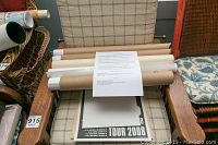 Rolled poster tubes and a partially visible poster reading 'Tour 2008' on a chair.