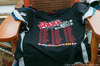 Black T-shirt printed with “The Police World Tour 2007-2008” title, tour dates list and international flags along the hem.
