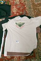 Photo of beige Rox Music T-shirt laid out flat showing front graphic, size label visible.