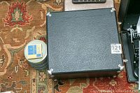Closed carrying case and 8mm film reels grouped on a patterned carpet.