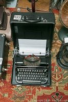 Open carrying case with Underwood Champion typewriter inside on patterned carpet