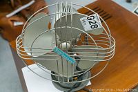 Front view of Sea Breeze metal fan showing blades, protective wire cage and brand logo.
