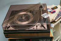 Dual 1214 turntable with dust cover placed on a stand next to folded clothes.