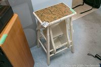 Photo of wooden step stool showing white painted frame with chipping paint and faux wood patterned top surface.