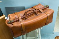 Front profile of brown leather Gladstone bag on stool showing overall shape and condition