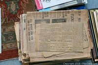 Stack of vintage newspaper clippings showing aged, yellowed paper with headlines and small articles.