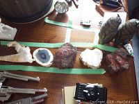 View of various petrified wood chunks, a round geode slice with a crystalline center, and carved owl sculptures on a wooden surface.