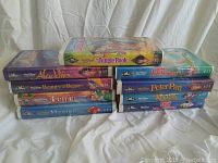 View of the lot showing 10 Walt Disney VHS tapes in their black diamond collection cases laid on a white background.