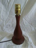 Full view of mid century teak table lamp showing shape and brass socket fitting on top.