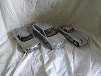Four silver model cars positioned against a white fabric background showing overall lot contents.