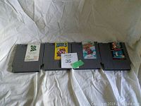 Four NES game cartridges displayed horizontally showing front labels. Titles visible include Super Mario Bros 2 and two variations of Super Mario Bros 3.