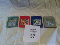 Four Nintendo Game Boy Pokemon cartridges in red, blue, gray, and crystal translucent blue casing with labels visible.