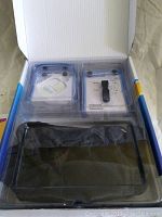 Boxed set showing main control unit, adhesive pads package, and clear plastic protective inserts