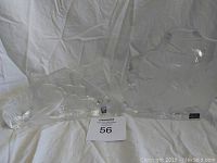 Two clear full lead crystal art glass sculptures placed on white fabric background with Mats Jonasson label visible.