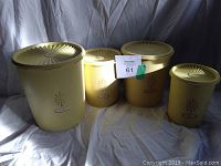 Four vintage mid-century Tupperware containers in harvest gold with lids, displayed in a single photo.