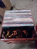 Top view of a wooden crate filled with approximately 50 vinyl records showing the Cheap Trick 'At Budokan' album at the front.