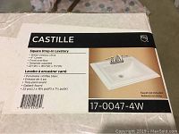 Photo of the box label showing brand Castillo, product name Square Drop-In Lavatory, product specifications such as white vitreous china, 4 inch center, front overflow, template supplied, and dimensions 22'x18.125'x7.5'.
