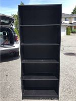 Front view of the black shelving unit showing all five shelves and a solid back panel.