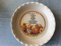 Top view of the white ceramic pie plate showing the pumpkin pie recipe and decorative pumpkins with sunflowers in the center
