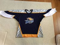 Front view of men's large navy blue hockey jersey with moose logo and silver, yellow accents
