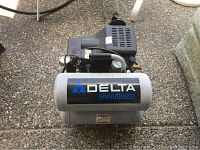 Front view of Delta ShopMaster air compressor showing branding on tank and motor assembly on top.