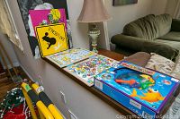 Magnetic fishing game in original box, magnetic crossword puzzle board with letter pieces, and yellow metal sign with black poodle silhouette visible on a wooden surface