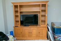 Front view of the wooden entertainment cabinet with shelves and TV placed in the center.