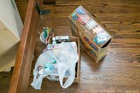 Overview showing assorted paints, paint brushes, and the box of cookie cutters on a wooden floor.