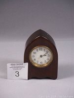 Front view of the dark wood polished mantel clock with white dial and black numerals.