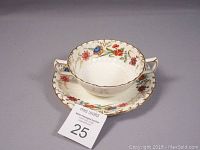 Bouillon cup and saucer angled showing floral pattern, gold rims, and embossed details