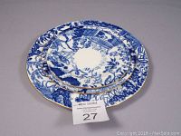 Three Royal Crown Derby Mikado collection plates stacked with the smallest on top, showing blue and white Oriental design and gold trim on scalloped edges.