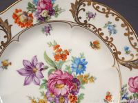 Close-up photo highlighting detailed floral pattern and gold scroll design on one china piece