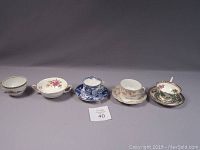 Five cups and their matching saucers displayed in a row showing variety of designs and styles.