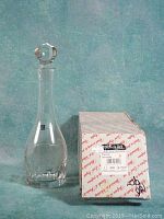 Full view of the decanter with stopper beside original Nachtmann box, showing clear lead crystal and round faceted stopper